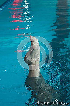 Synchronized swimming athlete trains alone in the swimming pool. Training in the water upside down. Legs peek out of the water. Stock Photo