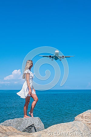 Synchronizing Dreams: Girl in White Meets a Plane Above the Blue Sea Stock Photo