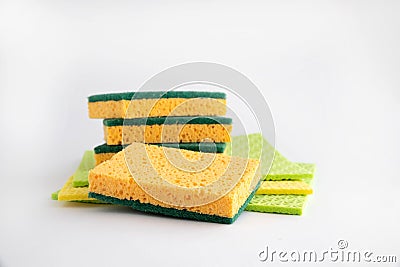 Synthetic sponges for washing dishes and rags for cleaning are in a pile on a white background. One sponge lies in front. Close-up Stock Photo