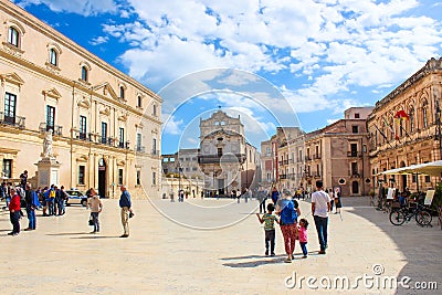Syracuse, Sicily, Italy - Apr 10th 2019: Tourists walking on the Piazza Duomo Square. Beautiful Santa Lucia Alla Badia Church Editorial Stock Photo