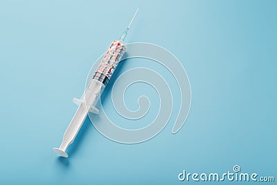 Syringe filled with colorful nano balls on a light blue background Stock Photo