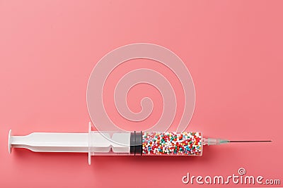 Syringe filled with colorful nano balls on a pink background Stock Photo