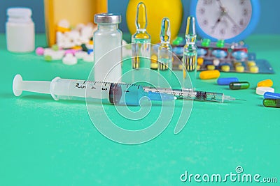 Syringe with glass vials and medications pills drug. In the background is a wood box and a yellow apple. Front views Stock Photo