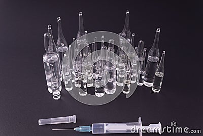 Syringe with medicine in front of ampoules on a black background Stock Photo