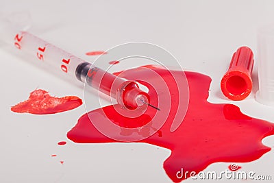 Syringe Squirting Red Blood onto White Background Stock Photo