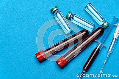 Syringe, test tubes with blood samples and ampoules with medicines or vaccine over blue background Stock Photo