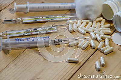 Syringe, thermometers, pills on a wooden background Stock Photo