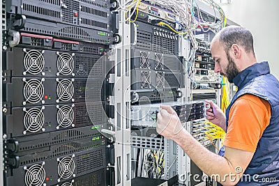 System administrator installs a new server in a modern data center. The specialist makes a backup copy of the computer database. Stock Photo