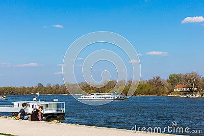 Tourist boat on Szentendre branch of Danube River on sunny day. Family resting on the shore. Space for text Editorial Stock Photo