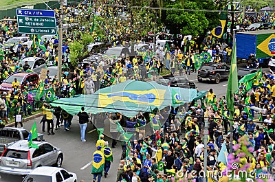 People parade carrying the Brazilian flag along the asphalt with the crowd Editorial Stock Photo