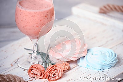 Fruit milkshake, sweet meringue desserts and tender flowers on a wooden coarse tray. light tender still life. summer snack Stock Photo