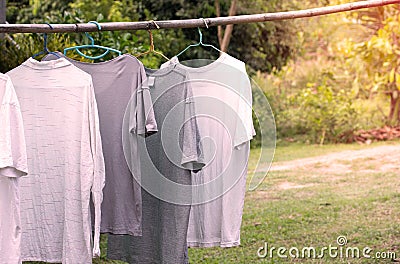 T-shirts hanging on wooden bar for dry after cleaning clothes in the garden outdoor Stock Photo
