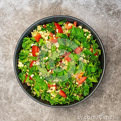 Tabbouleh salad with bulgur, parsley, spring onion and tomato in bowl on grey background. Top view Stock Photo
