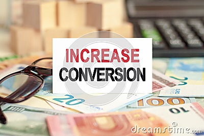 On the table are bills, a bundle of dollars and a sign on which it is written - INCREASE CONVERSION. Finance and economics concept Stock Photo