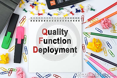 On the table is a calculator, diary, markers, pencils and a notebook with the inscription - Quality Function Deployment Stock Photo