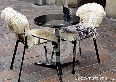 Table and chairs with fur cape outdoors near the restaurant Stock Photo