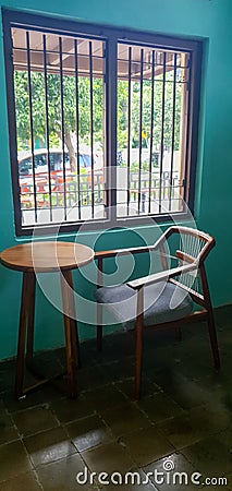 a table and chairs made of wood that were beside the wooden window as well. which has a classic motif Stock Photo