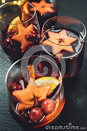 Table close-up still-life with Mulled wine with spices, fruits, cinnamon served in thin glasses. Hot beverages during cold season Stock Photo