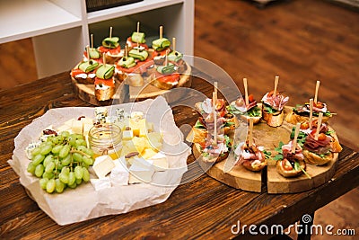 Table of cold party appetizers, set of cheese slices with grapes and cheese, two boards of cottage cheese tapas with salmon Stock Photo