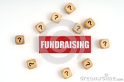 On the table are cubes with questions and a red plaque with the inscription - Fundraising Stock Photo