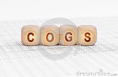 On the table with documents are wooden cubes with the inscription - COGS Stock Photo