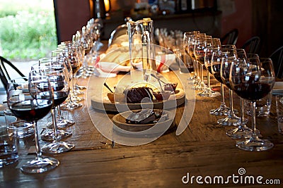 Table full of wine glasses filled with red wine and cheese plater Stock Photo