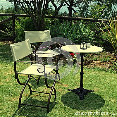 Table and iron chairs on green grass in the garden Stock Photo