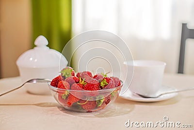 On the table in the kitchen is a hundred of a bowl of strawberries Stock Photo