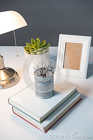 Table lamp, picture frame and books on table Stock Photo