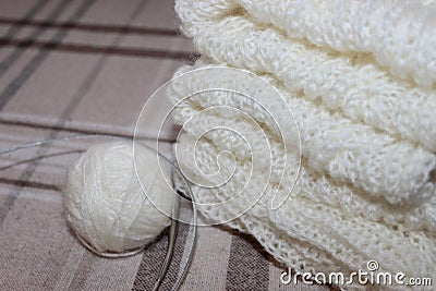 on the table lies a light sweater knitted with knitting needles and balls of threads Stock Photo