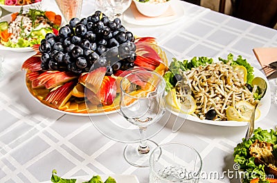 Table lined with variety of dishes from which the centerpiece is dish with sliced fruit Stock Photo