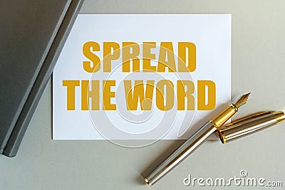 On the table are a notebook, a pen and a business card with the inscription - SPREAD THE WORD Stock Photo