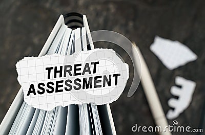 On the table is a notebook on which lies a piece of torn paper with the inscription - Threat Assessment Stock Photo