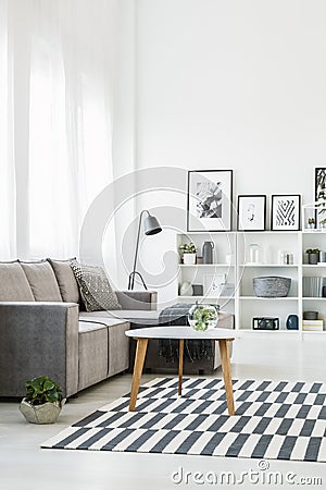 Table on patterned carpet in modern living room interior with gr Stock Photo