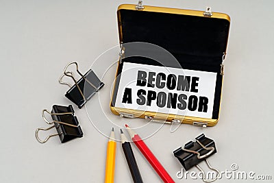 On the table are pencils and a business card holder, inside a business card with the inscription - BECOME A SPONSOR Stock Photo