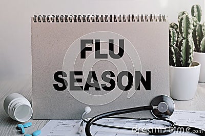 On the table are pills, a stethoscope, a cardiogram and a sign that says - FLU SEASON. The concept of medicine Stock Photo