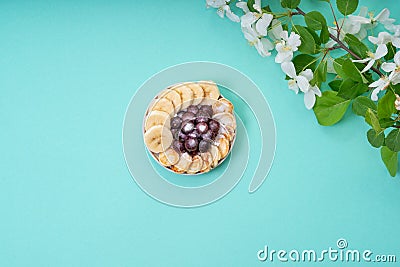 On the table is a plate with mini-pancakes, bananas and frozen currants Stock Photo