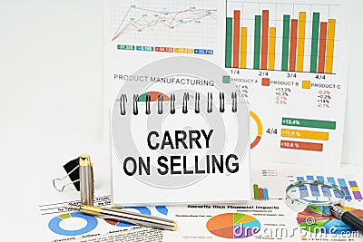 On the table are reports with graphs and a notepad with the inscription - Carry on Selling Stock Photo