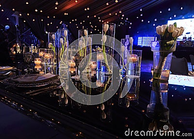 Table set with candles and tulip flowers decoration at night, indoor luxury wedding with low light romantic ambient Stock Photo