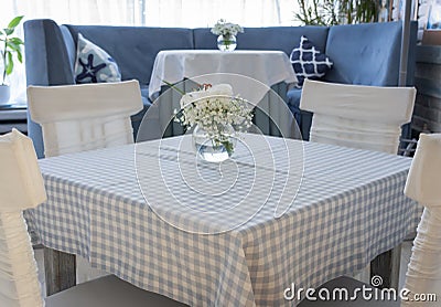 Table setting in restaurant in blue and white colors. Glass vase with white flowers on table in cafe. Stock Photo