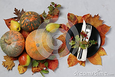 Table setting on Thanksgiving Day decorated pumpkin, viburnum, pears and colorful leaves on grey. Top view Stock Photo