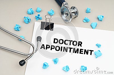 On the table is a stethoscope, a pen, blue crumpled pieces of paper and a sign with the inscription - DOCTOR APPOINTMENT Stock Photo