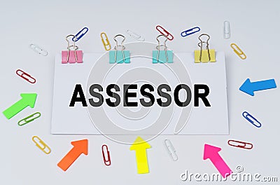 On the table there are paper clips and directional arrows, a sign that says - ASSESSOR Stock Photo