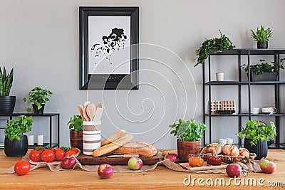 Table with tomatoes, bread, apples and herbs in a rustical dining room interior Stock Photo