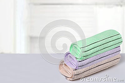 Table top on towels background. Closeup of a stack or pile of three soft terry bath towels at a bright table against blurred Stock Photo