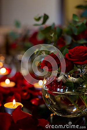 Vertical closeup photo of a transparent vase with a bouquet of dark red roses Stock Photo