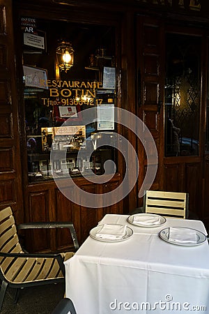Table With Two Chairs and White Table Cloth outside the restaurant Botin in Madrid, Spain Editorial Stock Photo