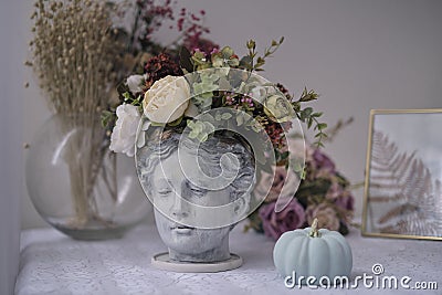 table by the window with interior details antique bust of Venus with flowers instead of hair Stock Photo