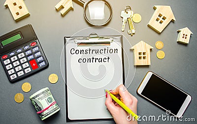 Table with wooden houses, calculator, coins, magnifying glass with the word Construction contract. Planning the construction of Stock Photo