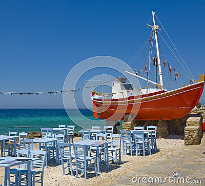 Tables in a tavern near the sea and the red boat Stock Photo